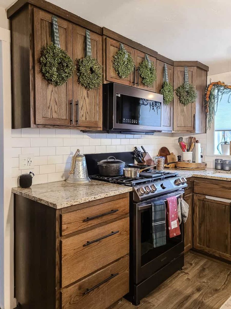 https://www.makingmanzanita.com/wp-content/uploads/2023/11/kitchen-cabinet-with-wreaths-hanging-on-doors-768x1024.jpg