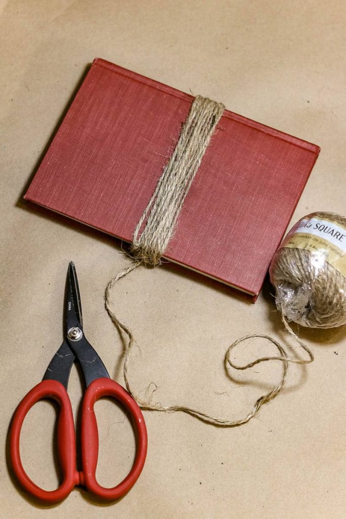 A photo of a red book with twine and scissor. 