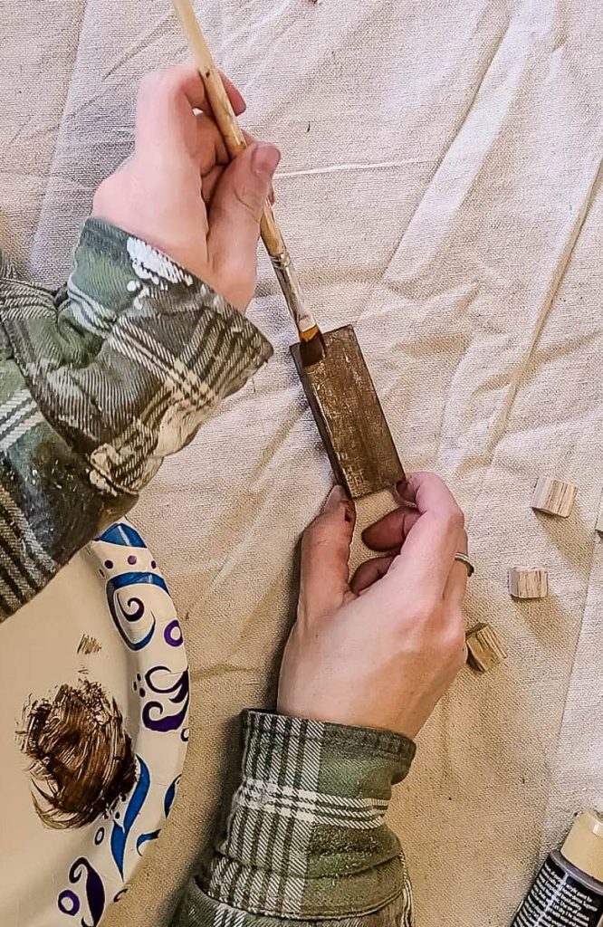 A person is painting a wooden nativity scene by hand.