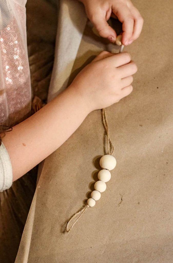 A person attaches wooden beads to a string.