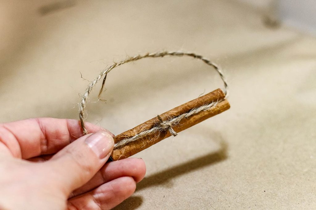 A twine tie and cinnamon sticks to make a macrame Christmas ornament.