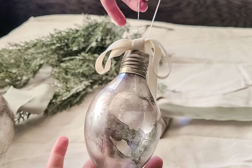 A finish product of DIY Mercury Glass Christmas Ornaments wit ribbon on top.
