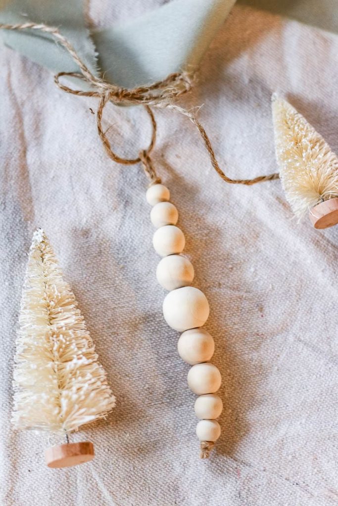 The photo shows wooden beads on the twine with tiny white Christmas tree ornaments.