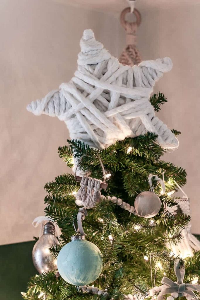 A cute little star made of cardboard and wrapped in yarn is perched at the top of a Christmas tree. Follow this guide on  how to make a Christmas tree star. 