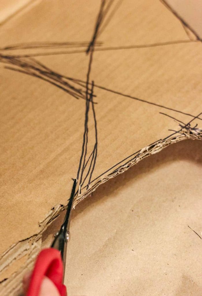 A star drawn on cardboard is cut with scissors. On how to make a christmas tree star.

