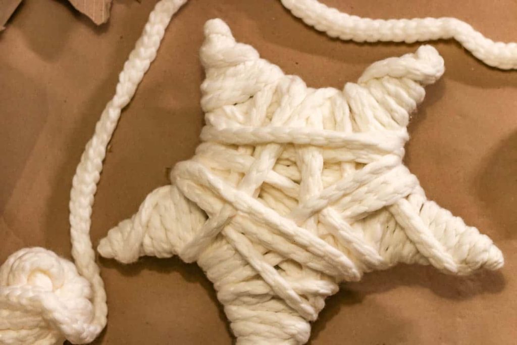 A simple cardboard star was covered with yarn on how to make a Christmas tree star.