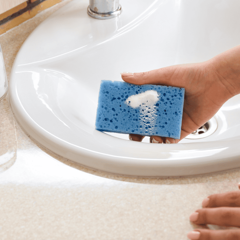 A person is cleaning the sink using baking soda paste