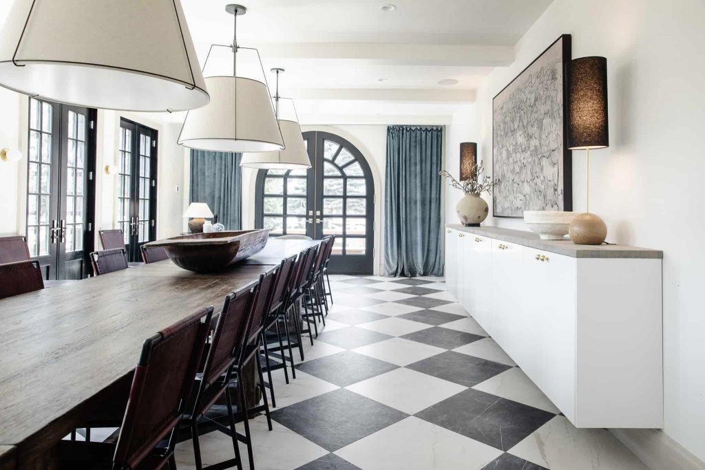 Black and cream Checkered tile floor in a dining room with large table, credenza and arch doorway