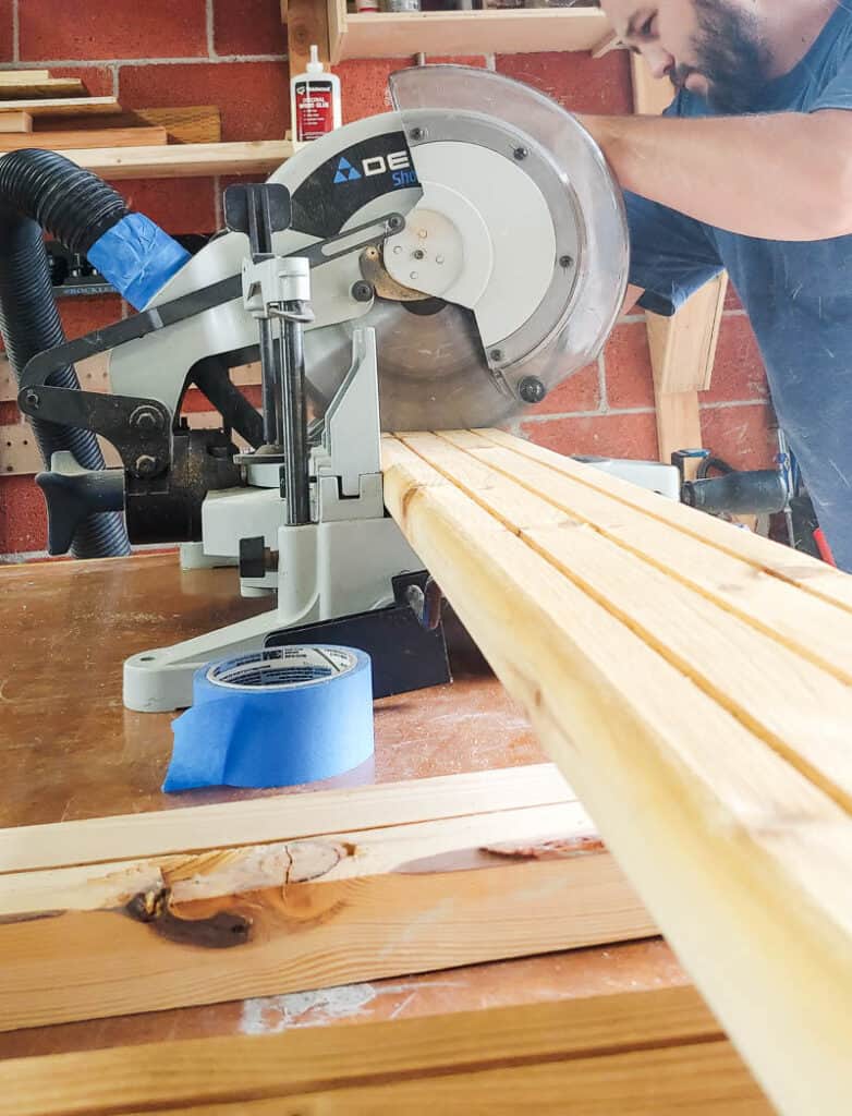 A man is utilizing a miter saw to precisely cut wood to the desired size.