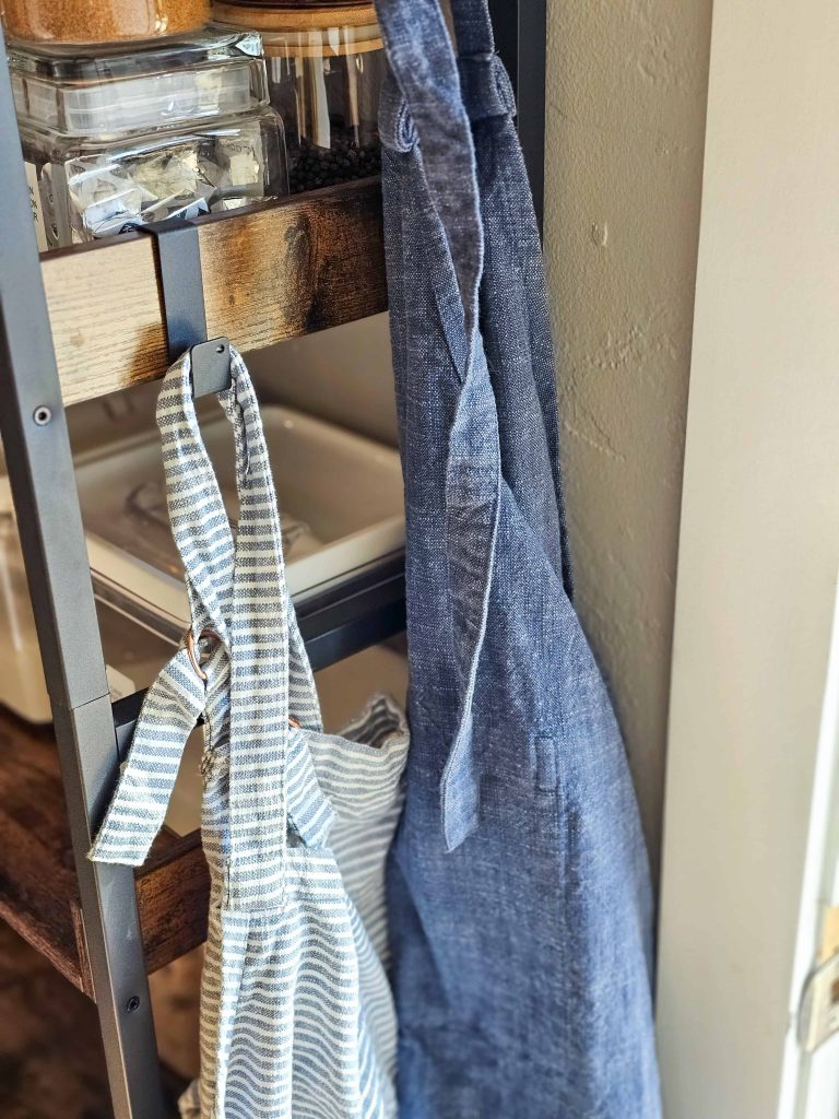 An image capturing aprons hanging from hooks on the side of the shelves.