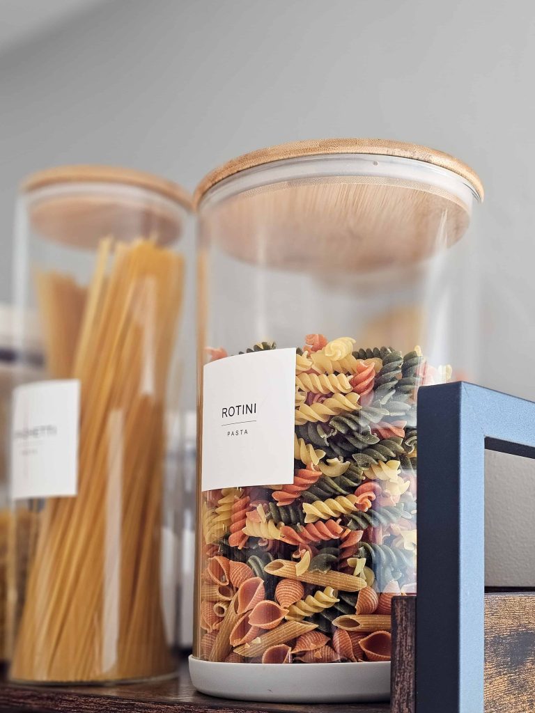 A close-up image displaying pasta stored in a container on the shelves.