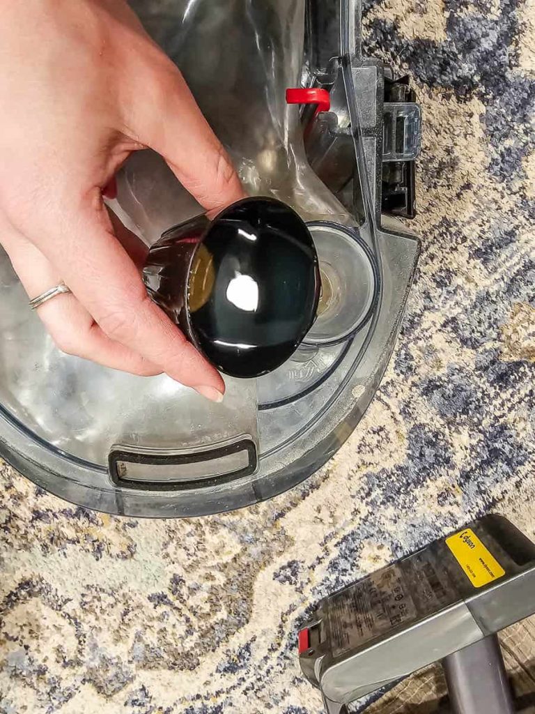 In the photo, a person is seen applying shampoo to a carpet cleaner.
