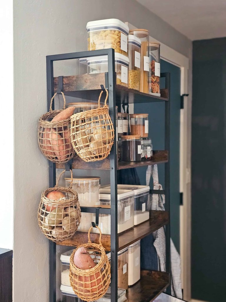 A kitchen pantry displaying neatly arranged food containers on shelves, with a basket placed to the side.