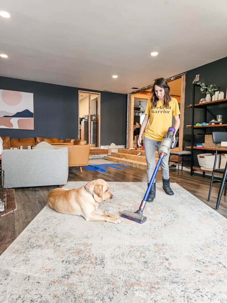 A woman is using a vacuum cleaner to clean the carpet in the living room.