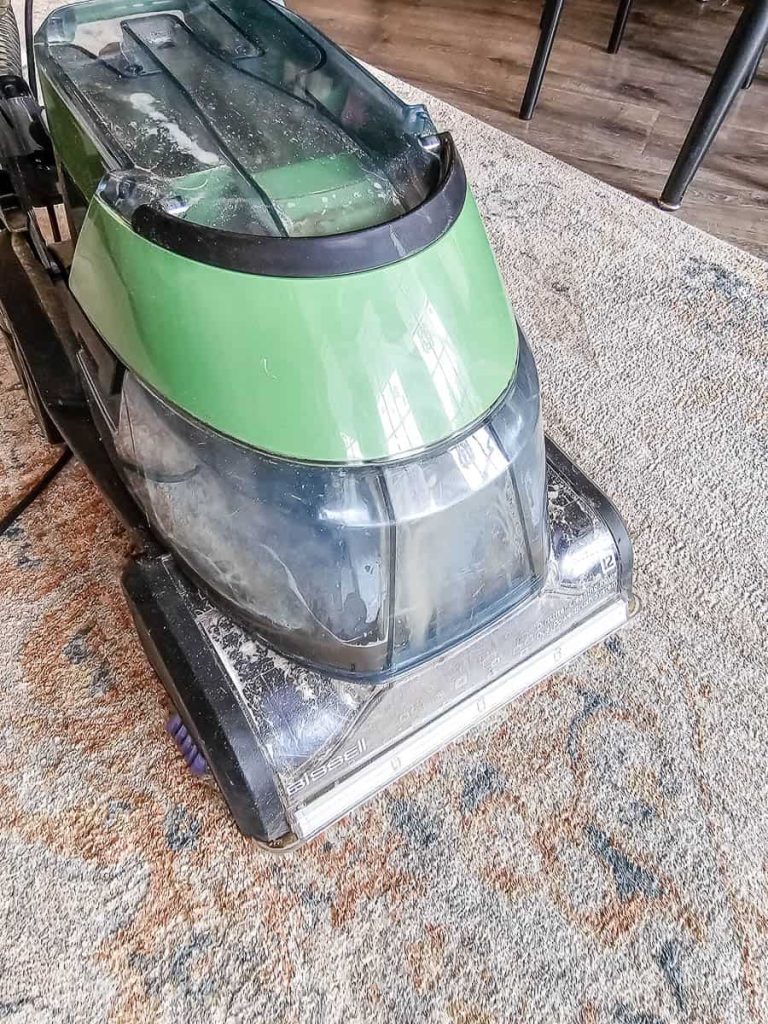 The photo displays a carpet cleaner being used to clean the carpet.