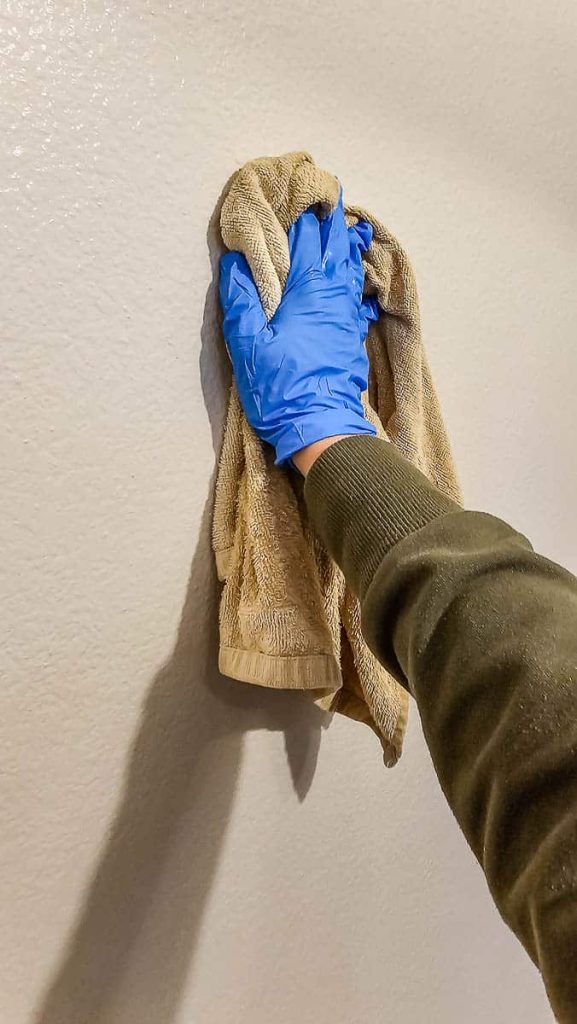 The initial steps of your Peel and Stick Wallpaper project with a photo of someone wiping and cleaning the wall.