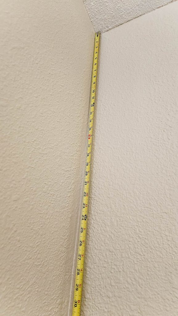 Capture the preparation phase with a photo of a measuring tape against the wall, getting ready for your Peel and Stick Wallpaper project.