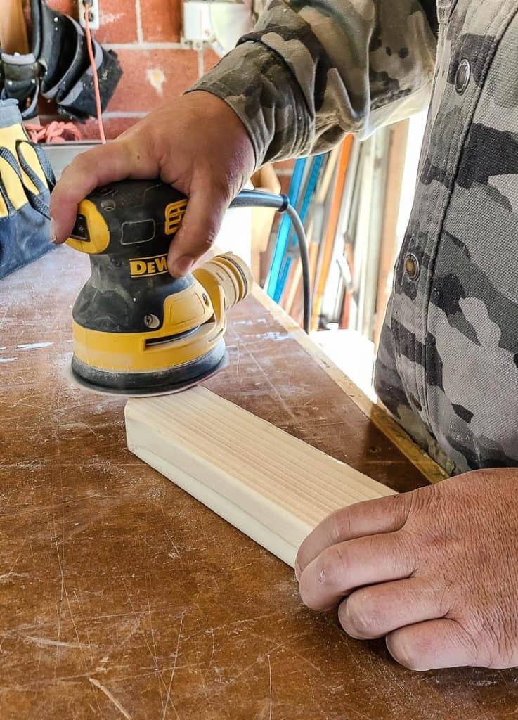 Man sanding piece of wood with Dewalt orbital sander