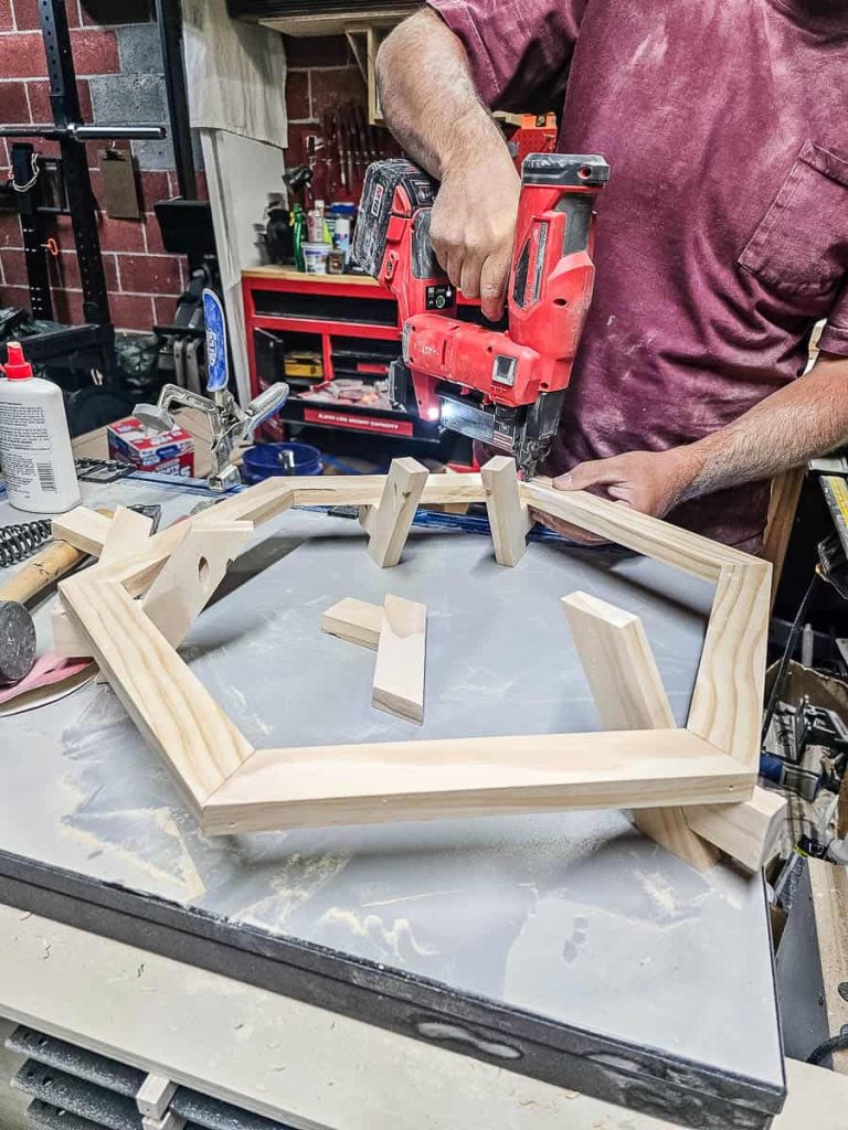 The man is applying glue and attaching the legs to the table.