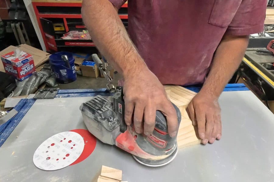 The man is sanding the Chicknic Table.