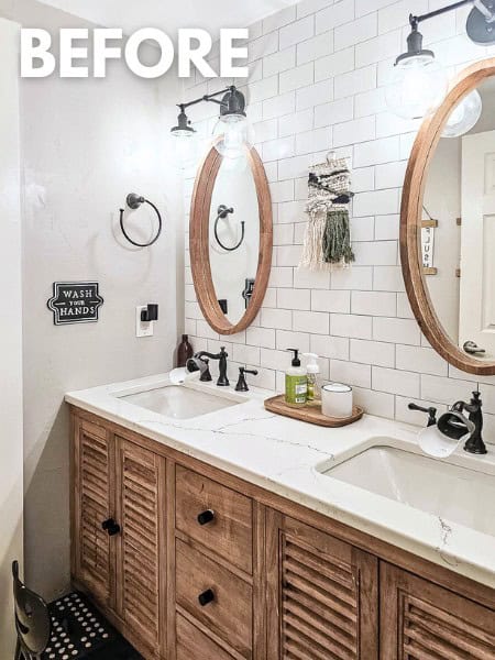 Bathroom with dual sink vanity with wood oval mirrors and a white subway tile wall with black faucets and bathroom accessories with text overlay that says "before"