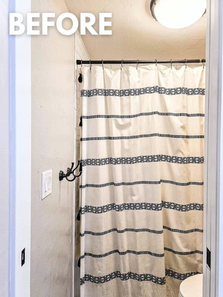 Bathroom with black and white boho shower curtain and oil rubbed bronze towel hooks and gray painted walls with text overlay that says "before"
