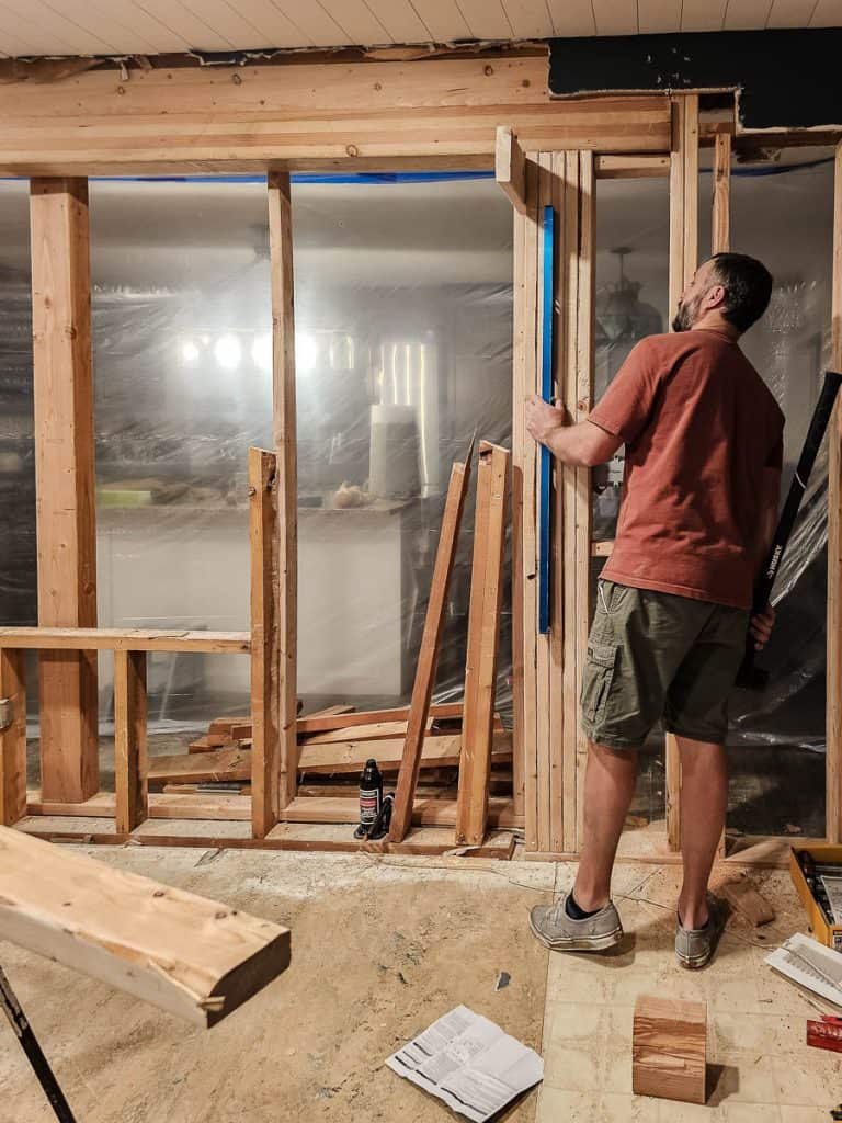Checking wall studs for level after adding the header beam into wall