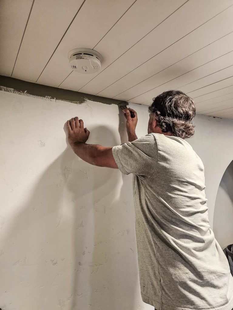 A photo of a man painting a wall, focused on creating an even layer of paint for a professional result.