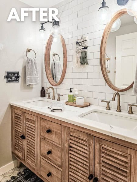 Bathroom with white subway tile backsplash wall behind wood vanity with two sinks with round wood mirrors and champagne bronze sink faucets and bathroom accessories with text overlay that says "after"