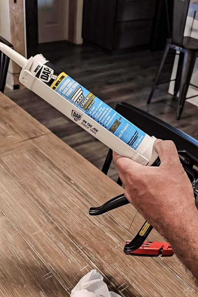 Another photo of a man loading DAP Alex Flex caulk into a caulking gun, ready to apply it for a home improvement task.