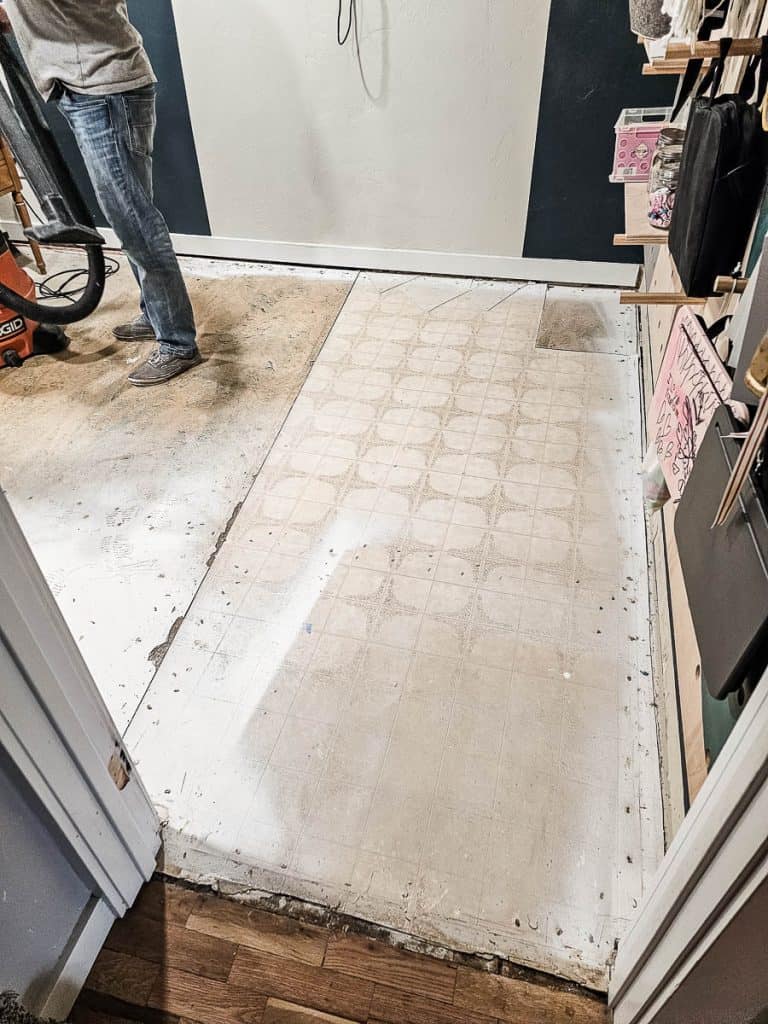 A photo showcasing the process of ripping out old carpet and installing laminate flooring.