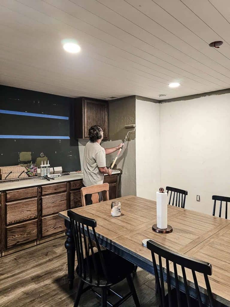 A photo of a man painting a ceiling, carefully applying paint with a roller for an even coverage.