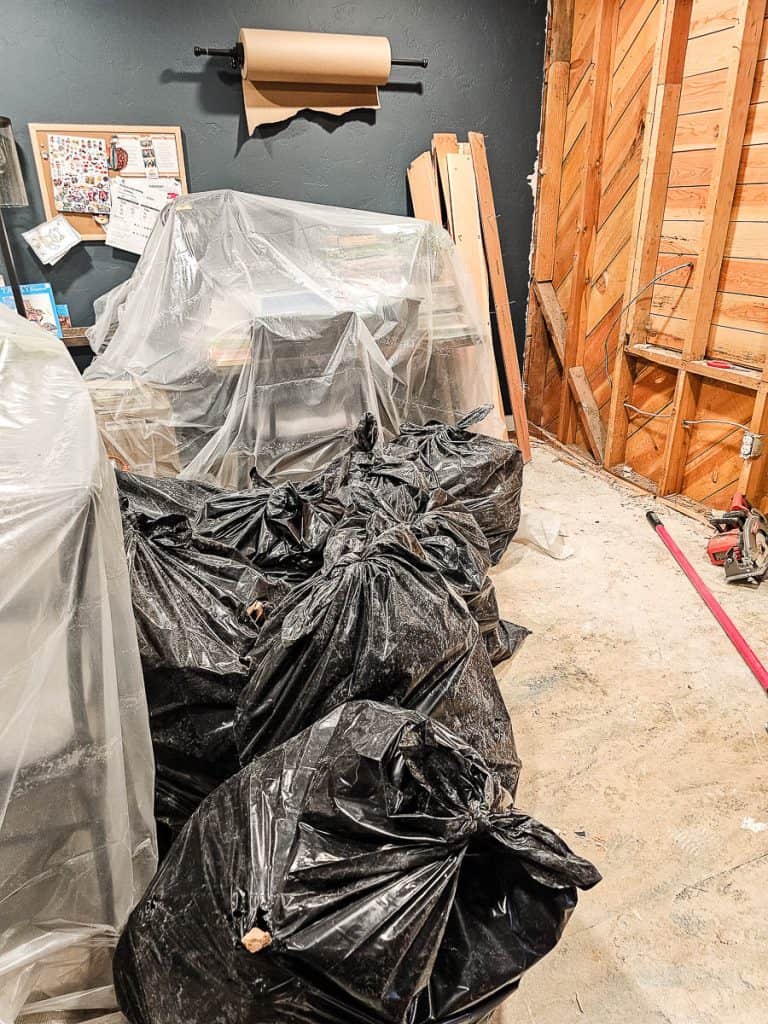 Several black heavy duty trash bags filled with renovation debris from removing walls