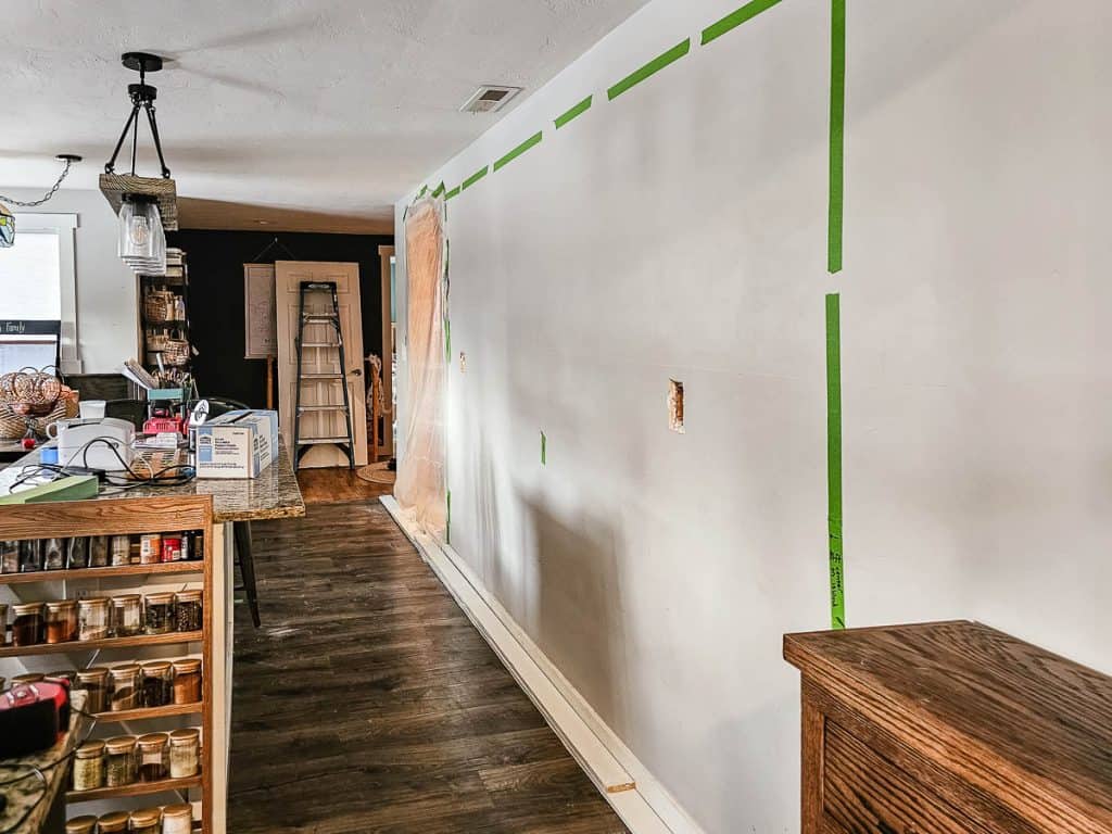 Wall in kitchen showing taped off section with painter's tape where the wall will be opened up to create an open concept