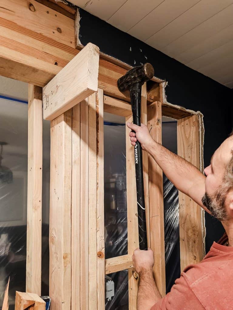 Tapping header beam into place with sledgehammer