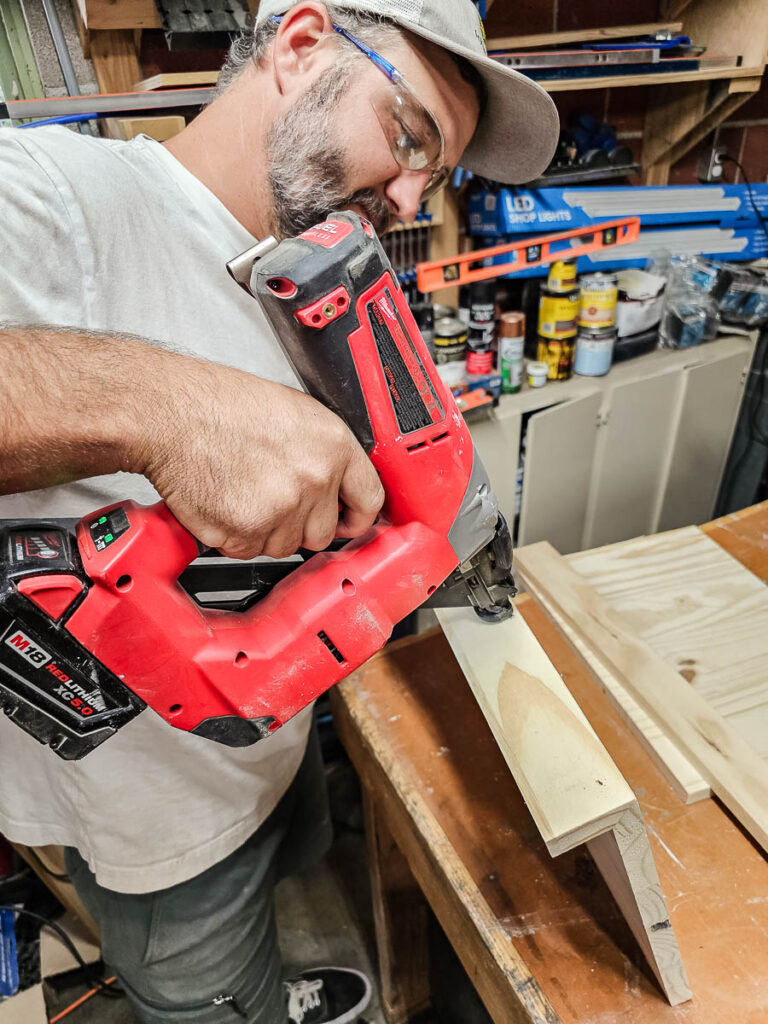 A man is assembling the floating bookshelves using a tool.

