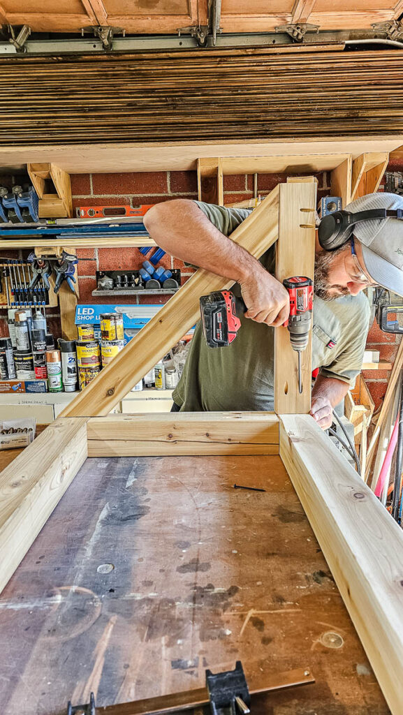 The next step is for the man to install the cross braces onto the 4x4s to build the DIY bike rack.