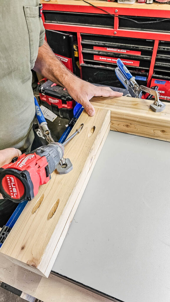 The man clamps the 4x4 posts into a rectangular shape, using pre-drilled pocket holes and 4-inch pocket hole screws, ensuring that the faces are square and flush while utilizing clamps as needed.