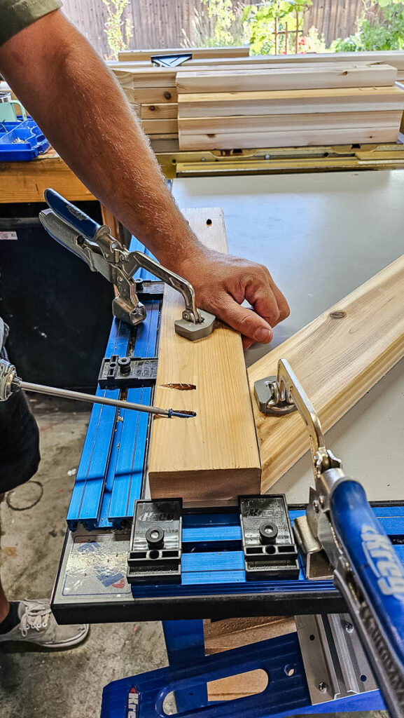 The man secures the 2x4 angled brace to the 2x4 bottom brace using 2½-inch pocket hole screws to build the DIY bike rack.