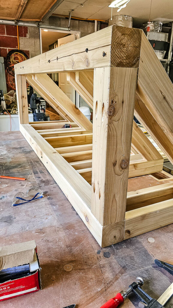 A photo of a wood securing the tops of the cross braces to build a DIY bike rack.
