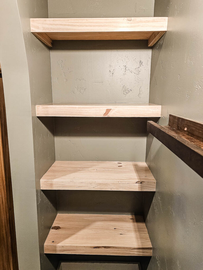 A photo of floating bookshelves already installed on the wall, with the painter’s tape finally removed.
