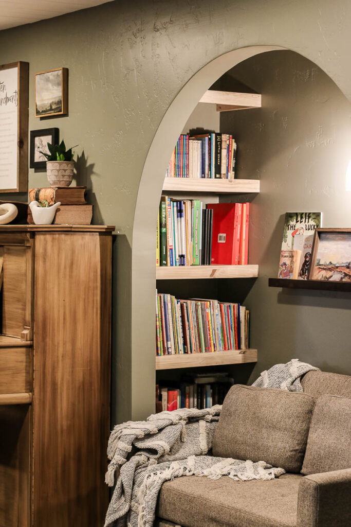 Small sofa in old closet turned into reading nook with wood bookshelves with an archway opening