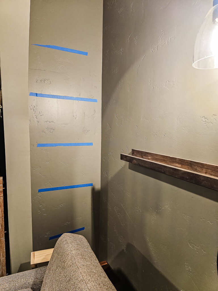 A photo of painter’s tape used as a guide for installing floating bookshelves on the wall.