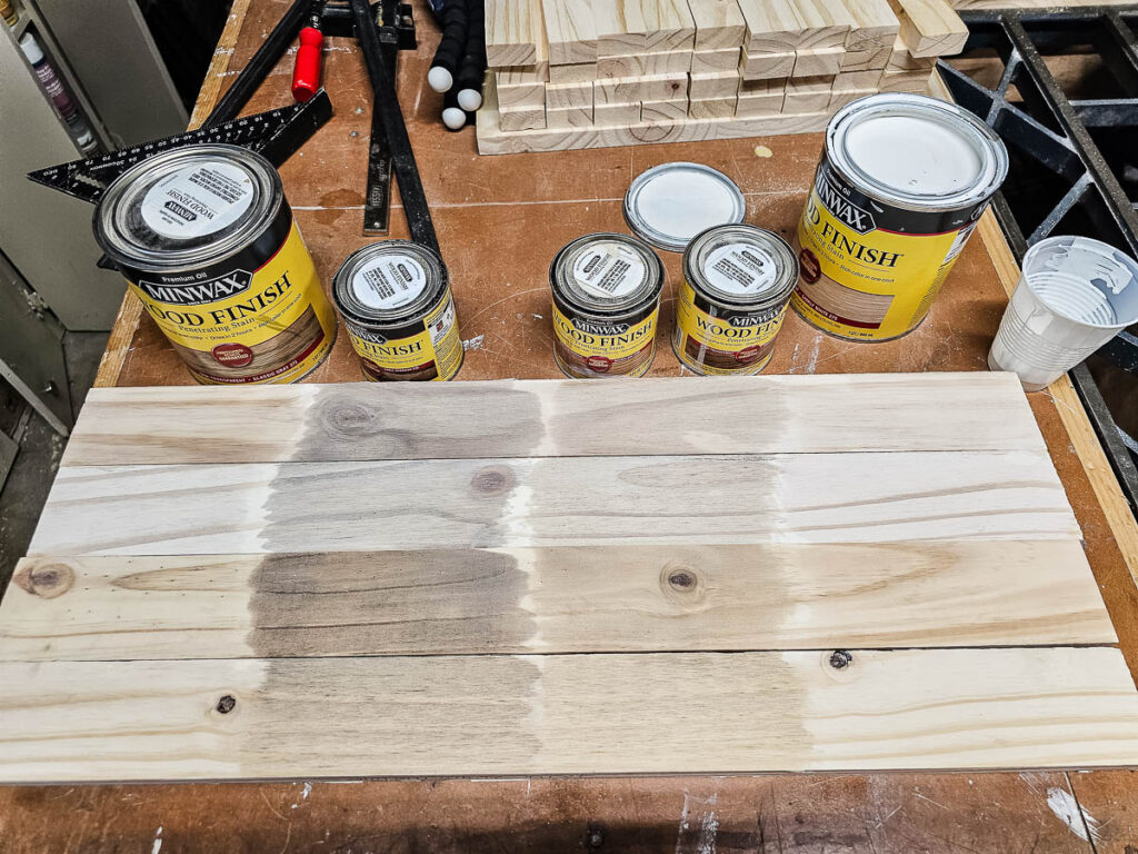 A photo of wood alongside cans of Minwax wood finish stain.