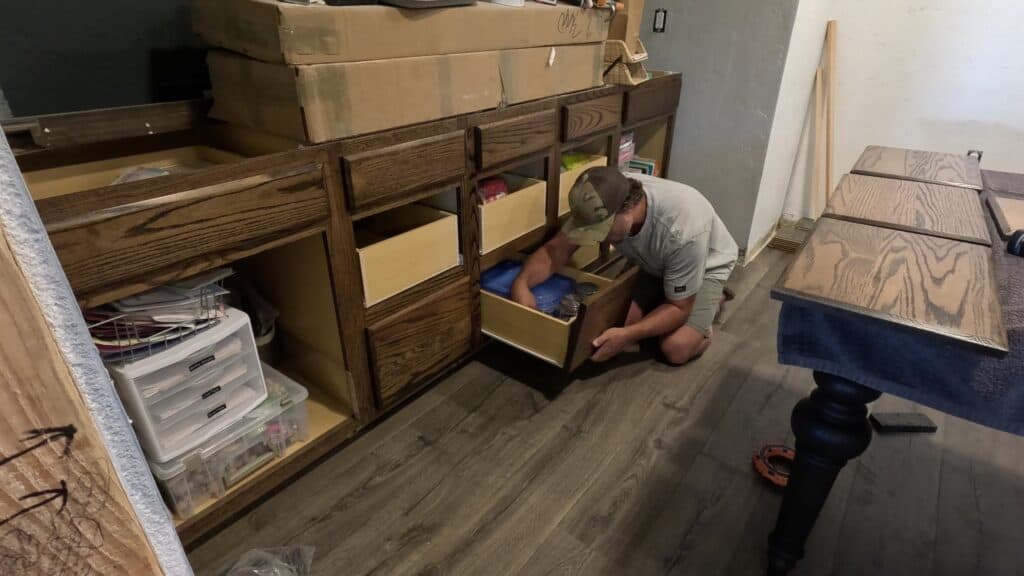 Installing drawer fronts back on to the base cabinets, crafted from stock cabinetry, in the process of being transformed for use in a dining room.