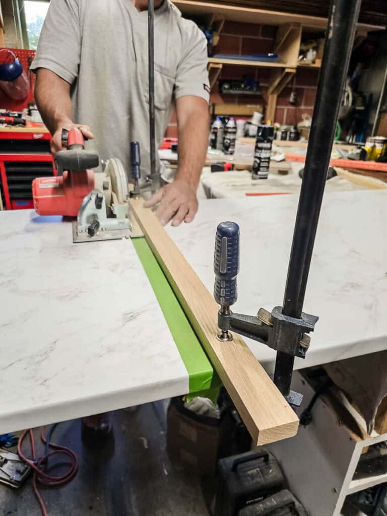 A photo of a man cutting a countertop down to size, preparing to install it as part of a DIY built-in cabinet project for a dining room using stock cabinetry.
