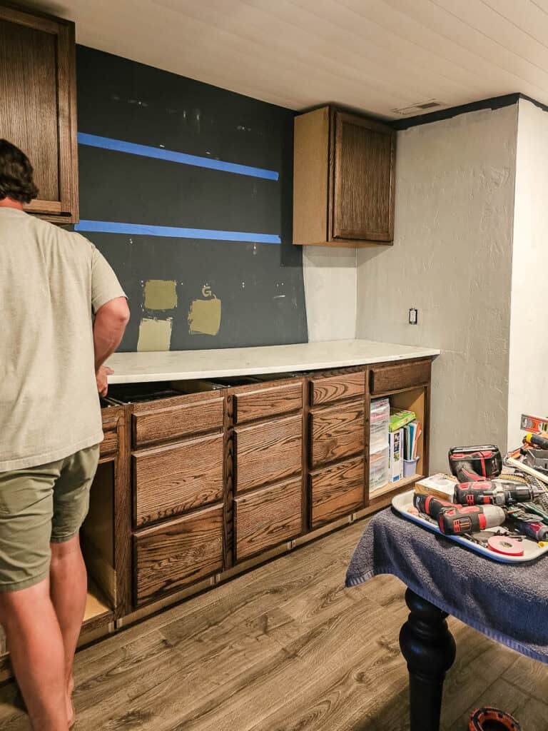 A photo of a man attaching the countertop as part of a DIY project to create built-in cabinets for a dining room using stock cabinetry.