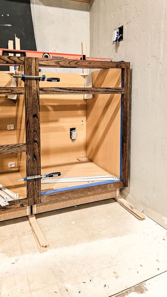 A photo of unfinished built-in cabinets for a dining room, constructed using stock cabinetry, showing the raw wood structure before painting or staining for a custom look.