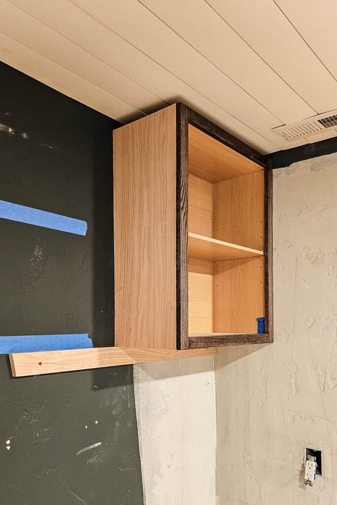 A photo of an installed upper cabinet made from stock cabinetry, showcasing its placement and functionality in a dining room setting.