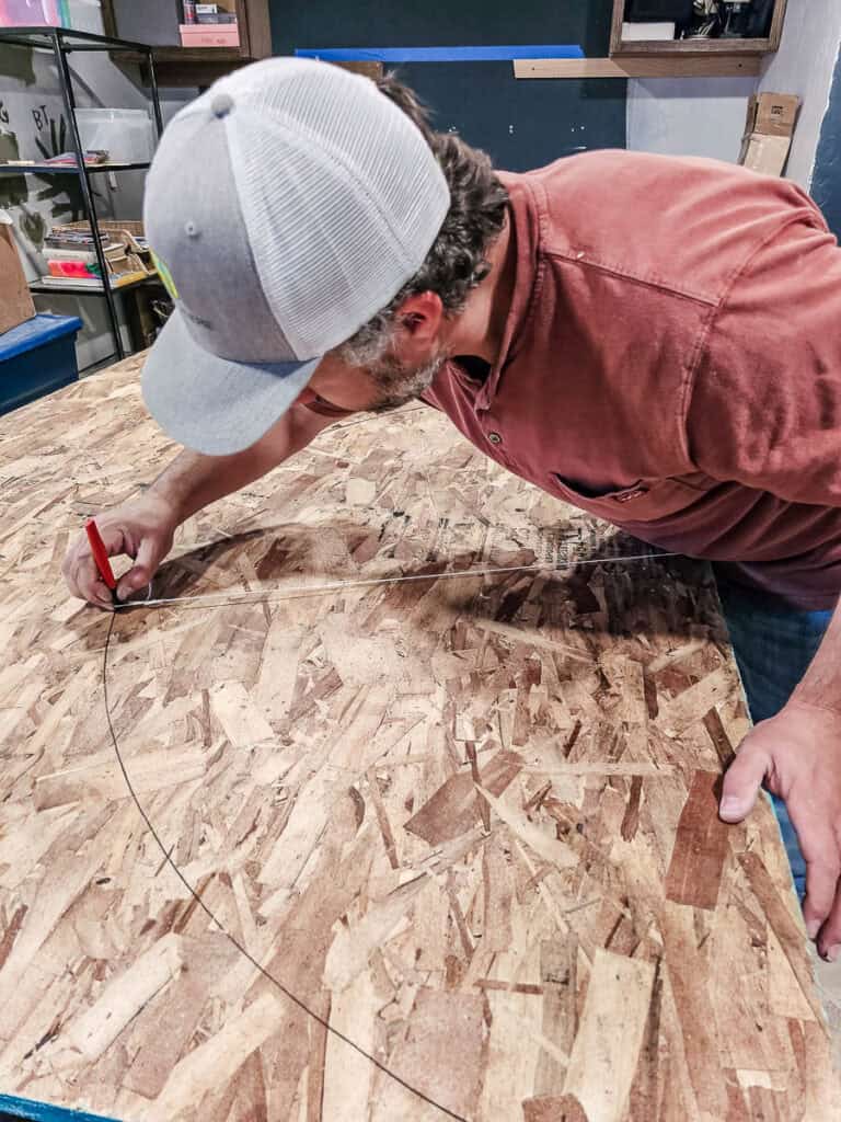 Marking an arch shape on sheet of OSB with a Sharpie marker and string to make arched opening 